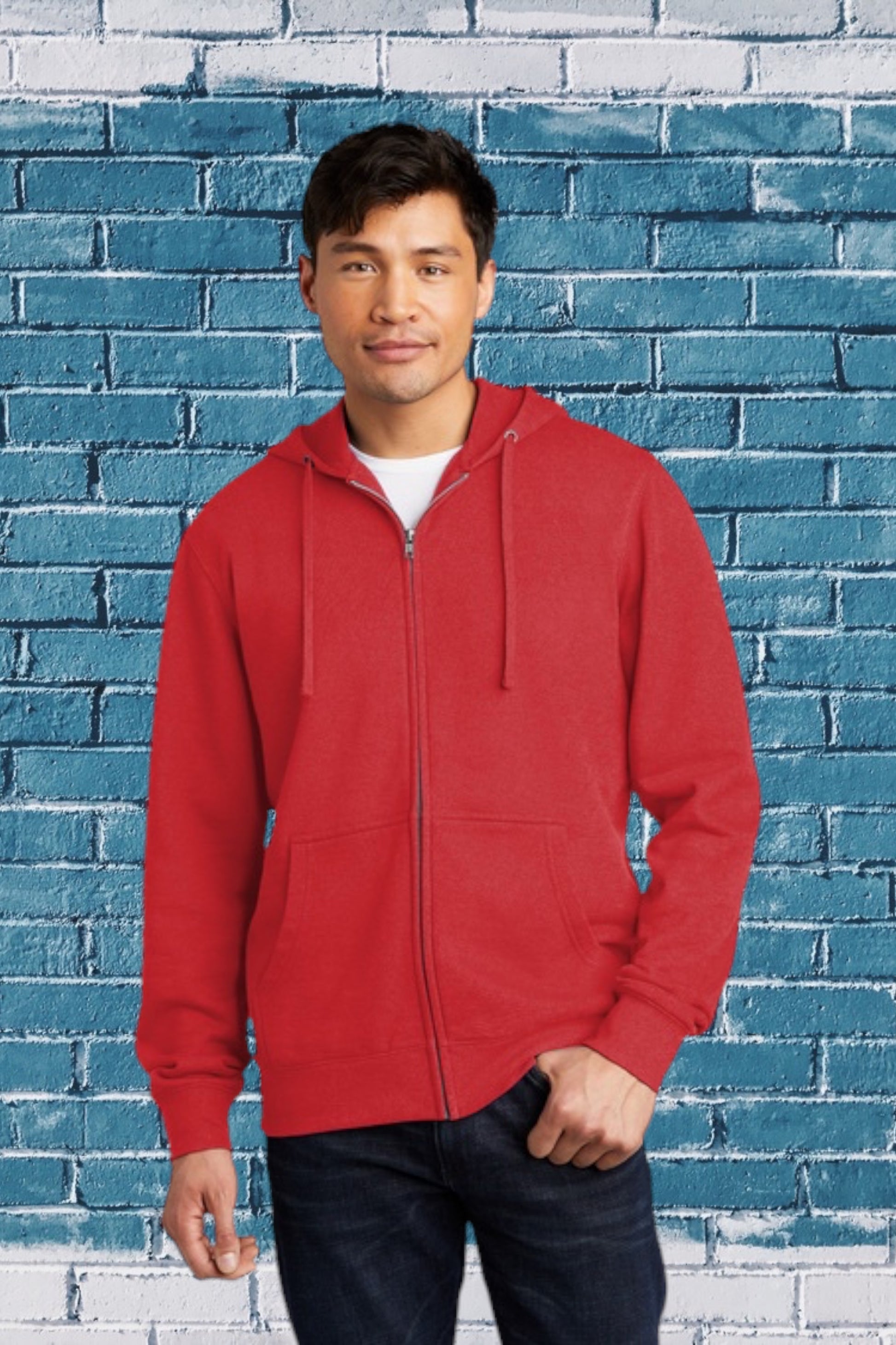 Man wearing a red hoodie standing in front of a blue brick wall